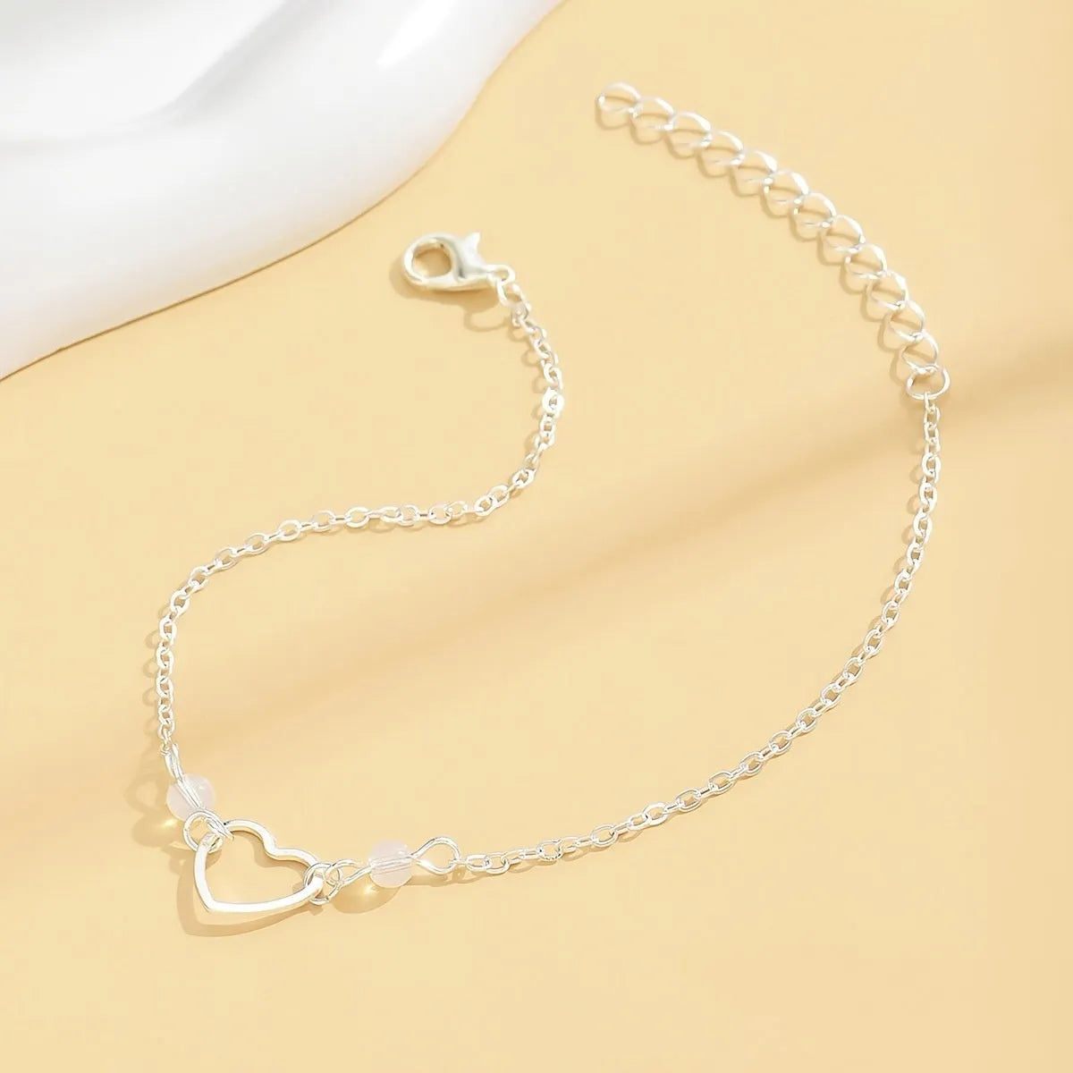 Gold and silver adjustable women's ankle bracelets with a small heart pendant on a chain.