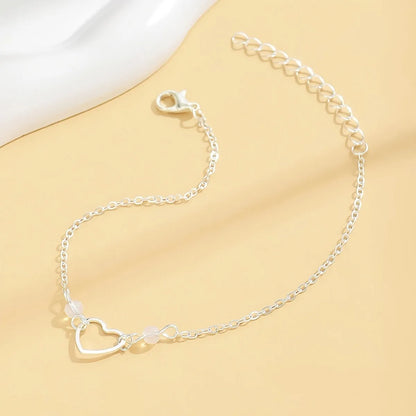 Gold and silver adjustable women's ankle bracelets with a small heart pendant on a chain.