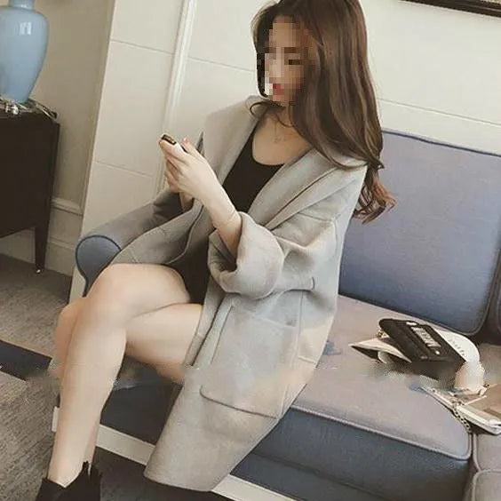 Plus size woman modelling a loose fit grey thin coat with lace detailing and long sleeves.