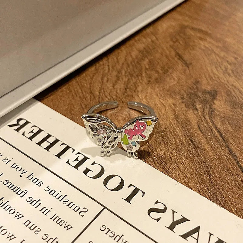 Copper butterfly women's ring with an open loop design on a plain background.
