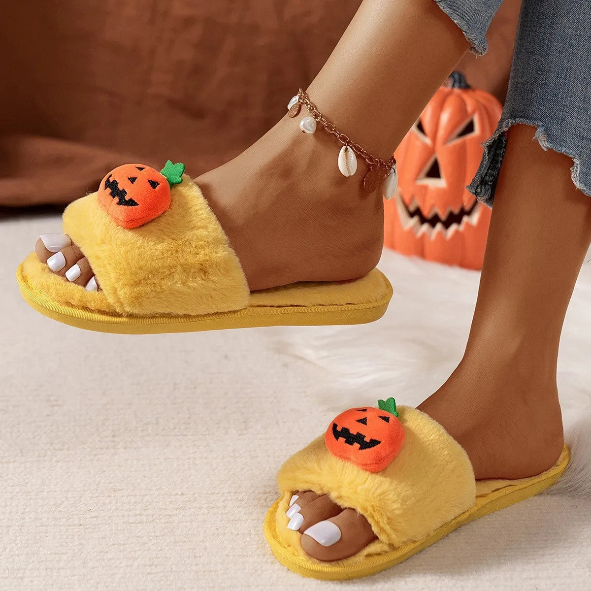 Yellow pumpkin plush open-toe slippers with synthetic fur and textured PVC sole on wooden floor.