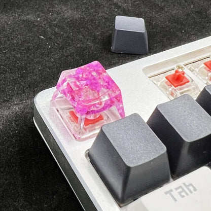 Transparent resin mechanical keyboard keycap with glitter starry sky effect in red, pink, green, or violet.