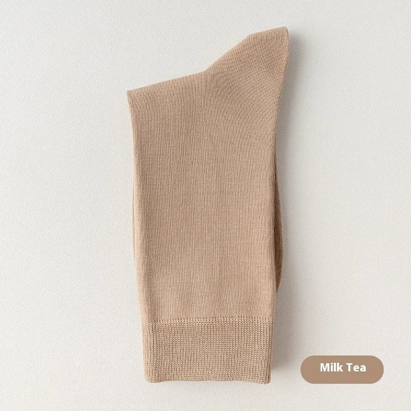 Pair of solid-colour men's mid-calf socks made from combed cotton on a wooden background