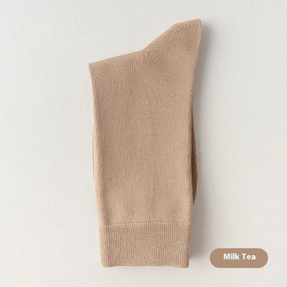 Pair of solid-colour men's mid-calf socks made from combed cotton on a wooden background