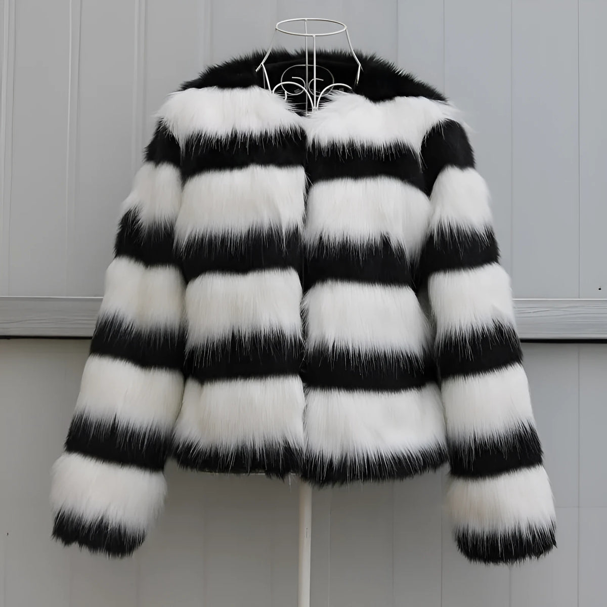 Womens black and white striped long-sleeved faux fur leather jacket on a hanger.