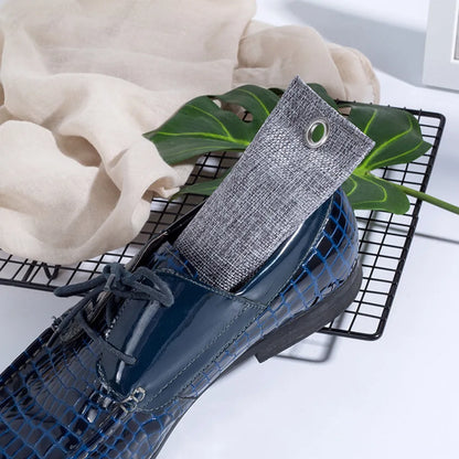 Set of black, green, grey, and blue rectangular bamboo charcoal deodorising bags on a white surface.