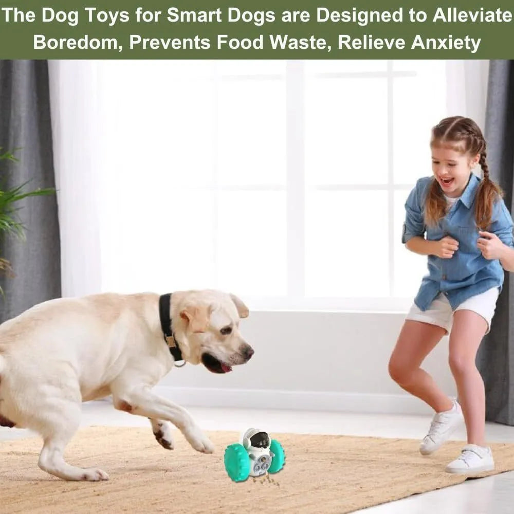 A black, robot-shaped treat dispenser toy for dogs and cats on a wooden floor, showing its size and rolling design.