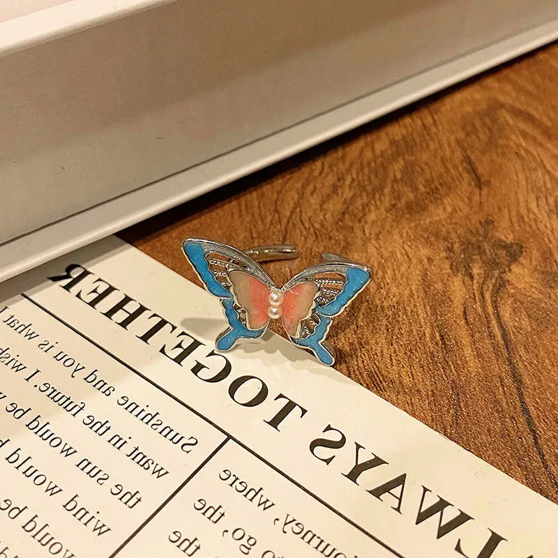 Copper butterfly women's ring with an open loop design on a plain background.