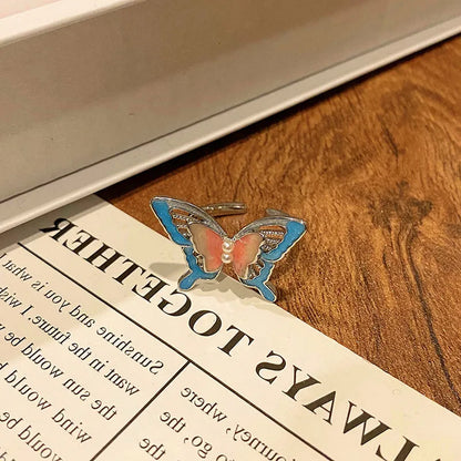 Copper butterfly women's ring with an open loop design on a plain background.