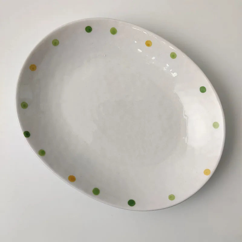 Japanese-style dot pattern porcelain plates and bowls in irregular oval and round shapes on a table.