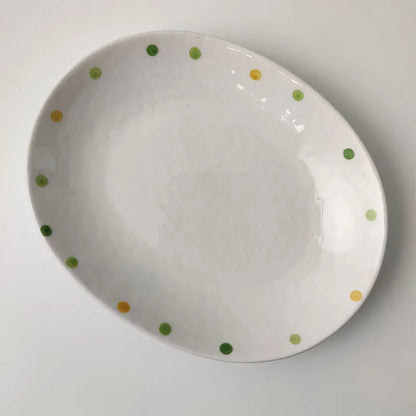 Japanese-style dot pattern porcelain plates and bowls in irregular oval and round shapes on a table.