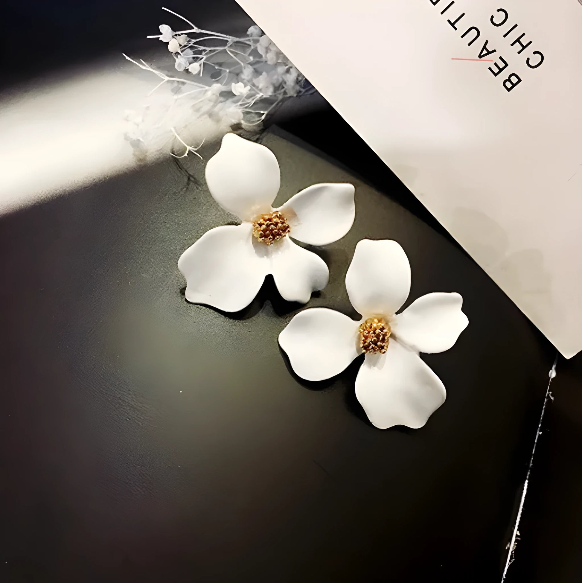 A pair of women's flower-shaped alloy stud earrings with a white electroplated finish.