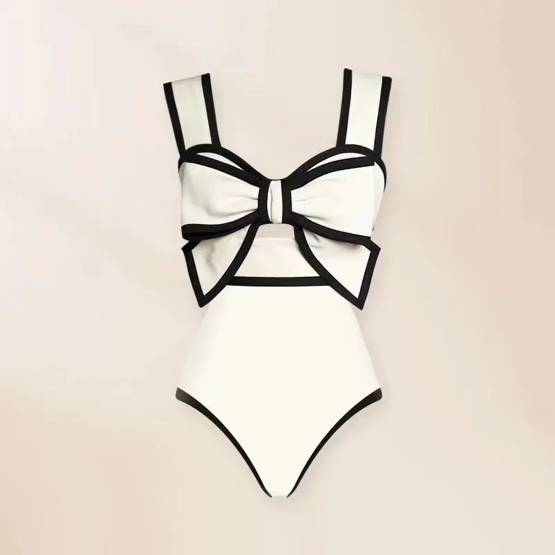 Women's black one-piece swimsuit with white attached round skirt and decorative bow at front