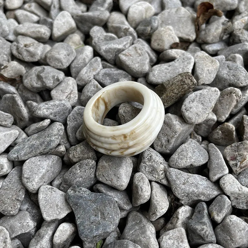Geometric Chinese-style wide resin ring in brown and white colours on a plain background.