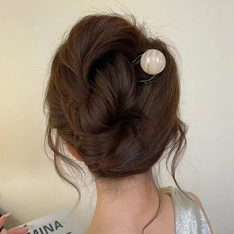 A set of U-shaped acrylic hair barrettes with a simple ball decoration in beige, caramel, and dark grey colours.
