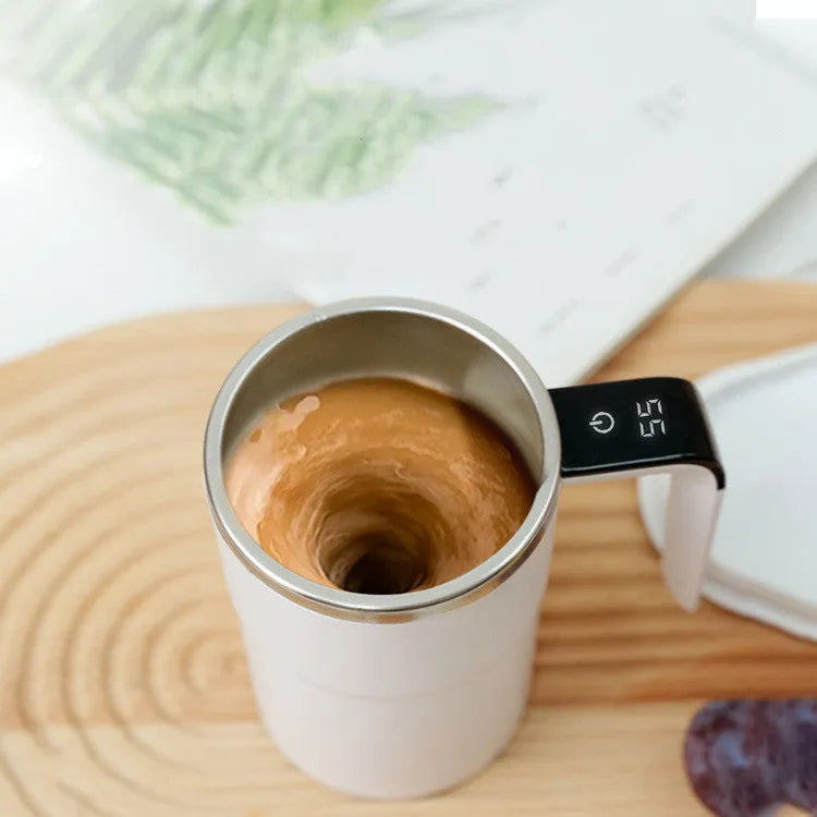 Electric coffee mug with USB charging port, magnetic stirrer, and LCD display showing temperature, in black or white colour.