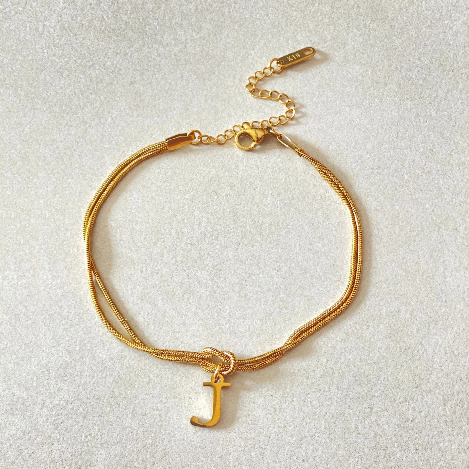 Elegant letter charm bracelets for women in gold and silver tones, featuring a delicate snake chain design and personalised letter charms.
