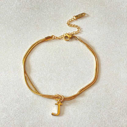 Elegant letter charm bracelets for women in gold and silver tones, featuring a delicate snake chain design and personalised letter charms.