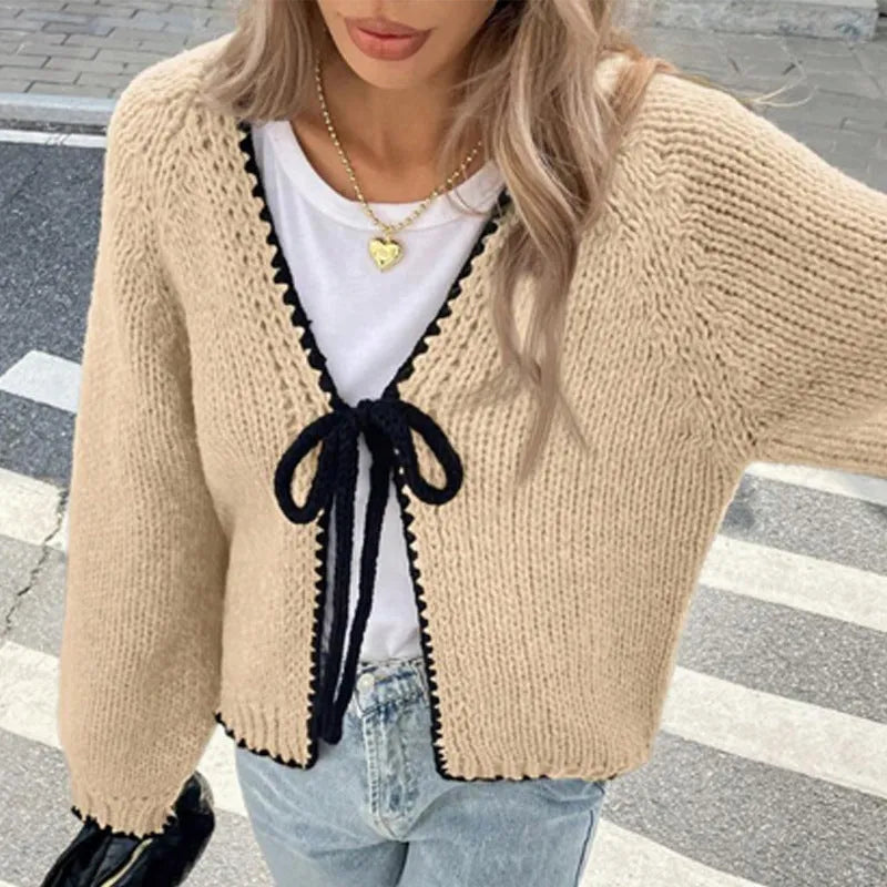 Grey lace-up front cardigan sweater with long sleeves and a crocheted flower detail.