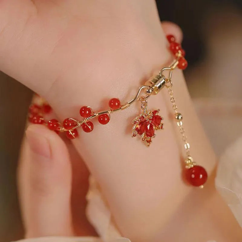 Red ginkgo leaf charm magnetic bracelet for girls on a wrist, showing maple leaf design details.