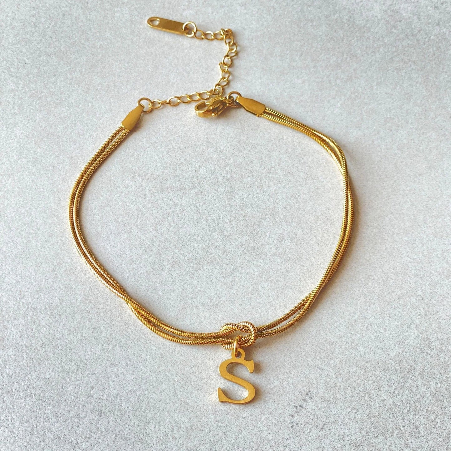 Elegant letter charm bracelets for women in gold and silver tones, featuring a delicate snake chain design and personalised letter charms.