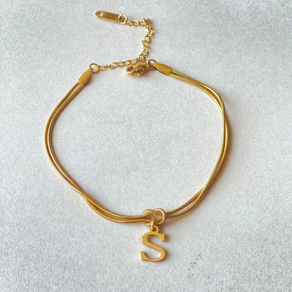 Elegant letter charm bracelets for women in gold and silver tones, featuring a delicate snake chain design and personalised letter charms.