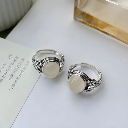 Adjustable open-mouth copper vintage ring with U-shape and antiqued white chalcedony-style finish on a wooden surface.