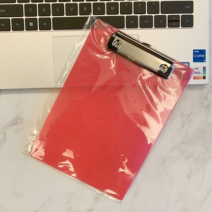 Transparent A4 plastic plate holder with metal clip, holding white paper, on a desk.