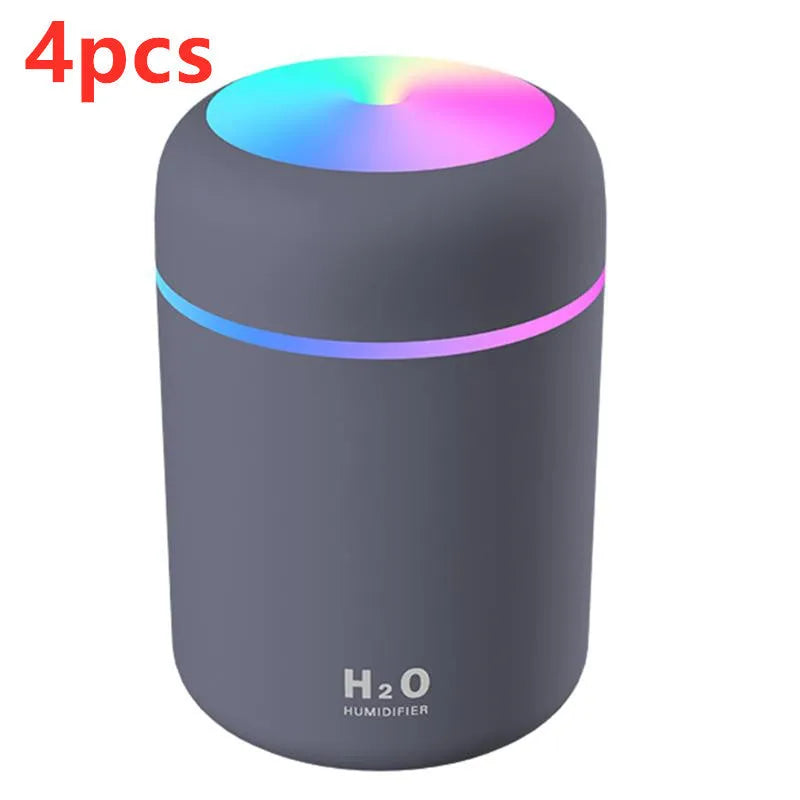 Pink USB desktop humidifier with LED lights and water tank on wooden desk