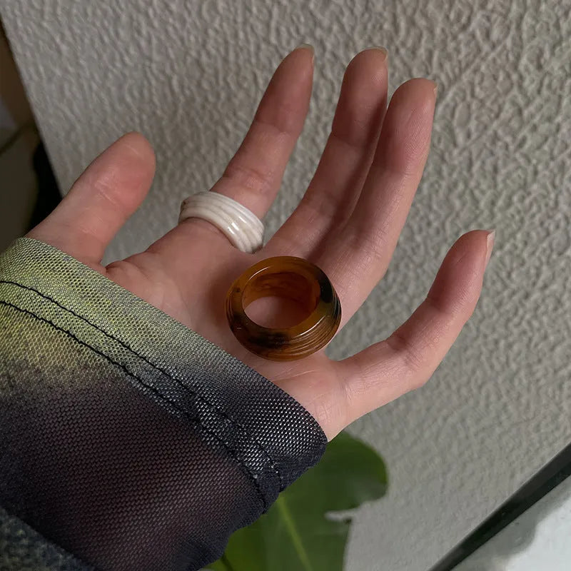 Geometric Chinese-style wide resin ring in brown and white colours on a plain background.