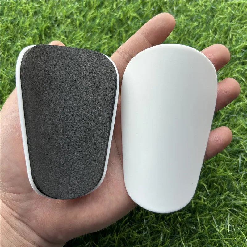 Extra small 8x5cm black and white plastic football shin guards for junior players.