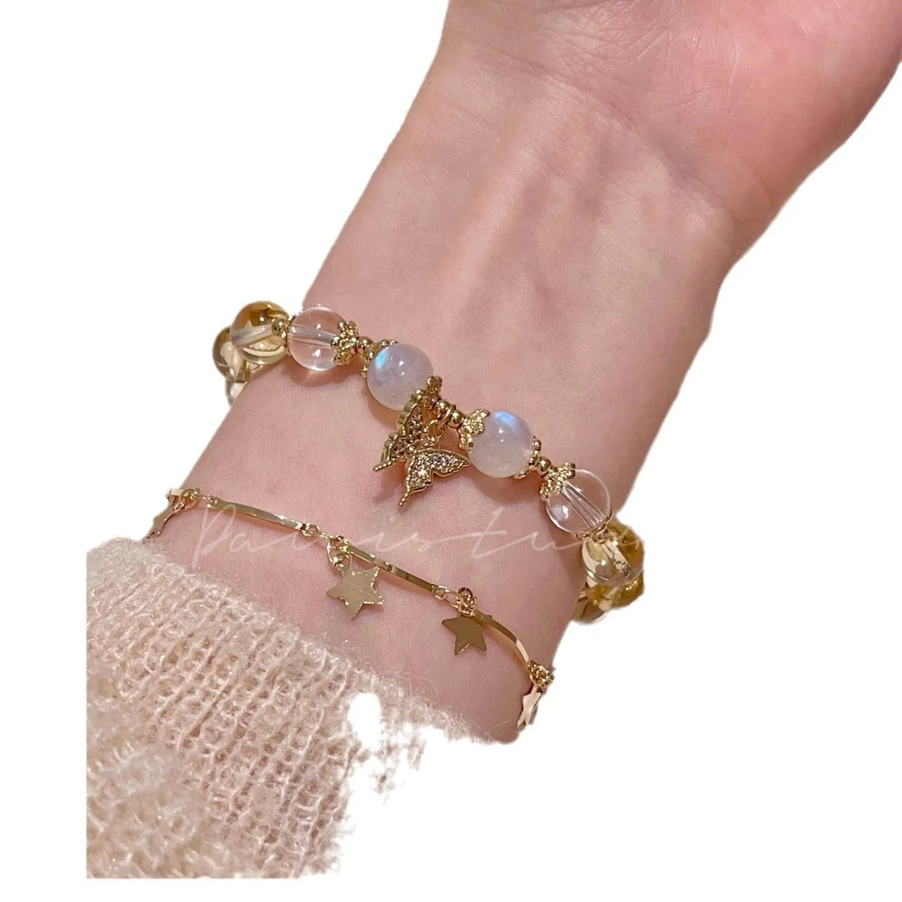 Close-up of a citrine-coloured crystal bracelet with diamond-shaped beads and a butterfly charm.