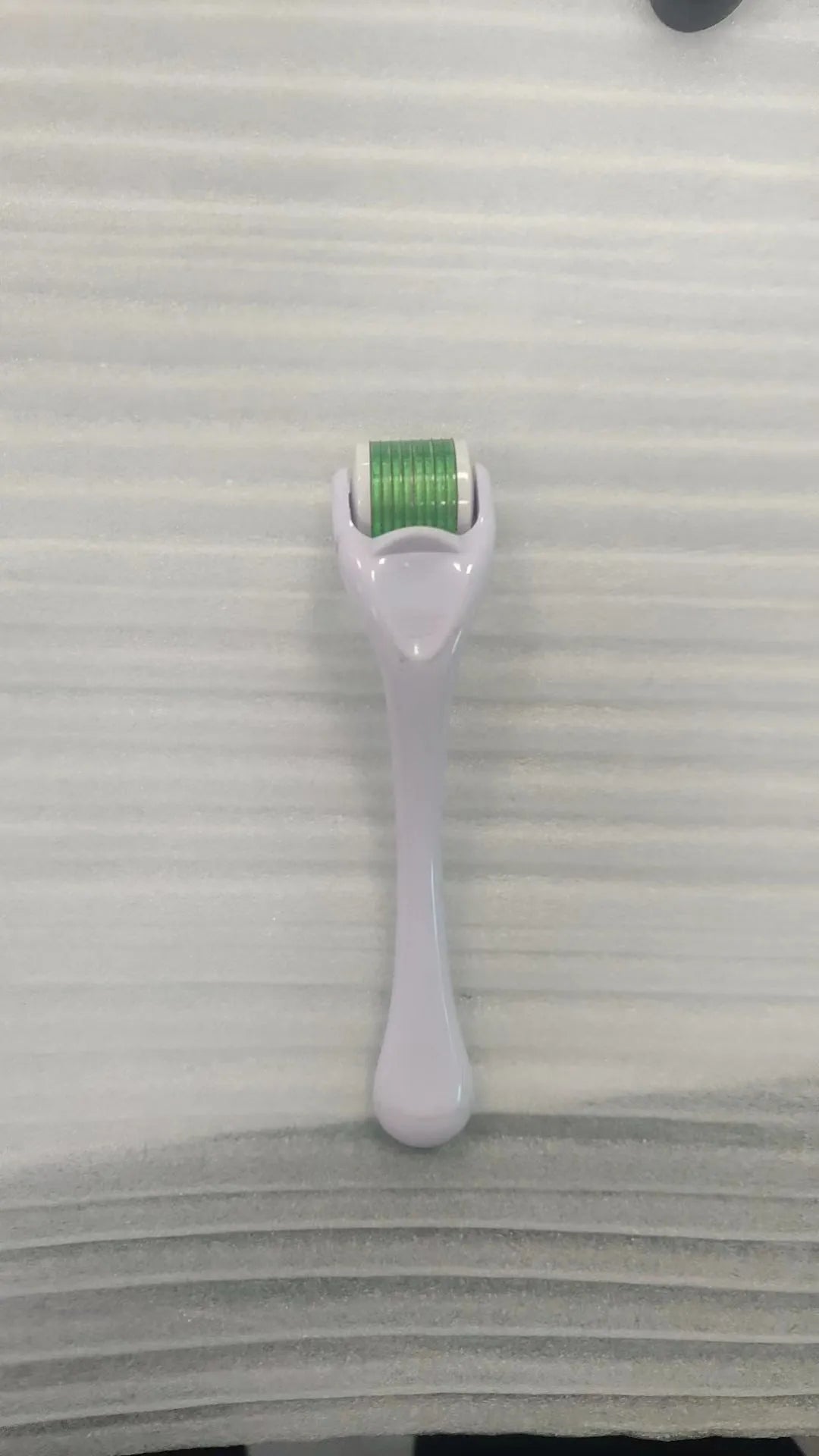 Sterile micro needle derma roller with black handle and coloured wheel on white background