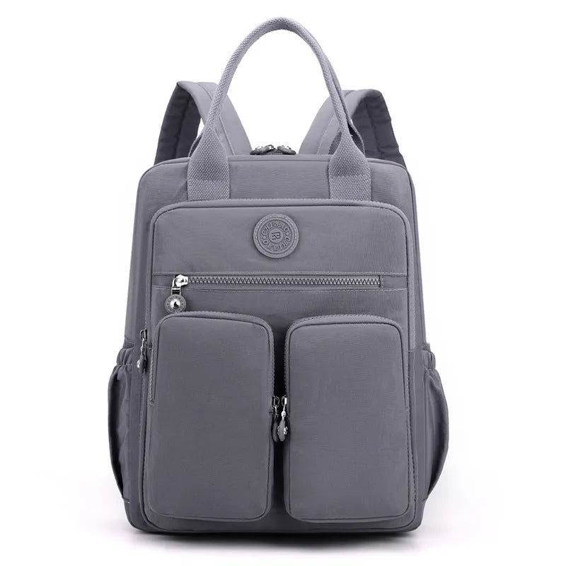 Women's waterproof nylon travel backpack in grey, showing front external pocket and organisational interior.