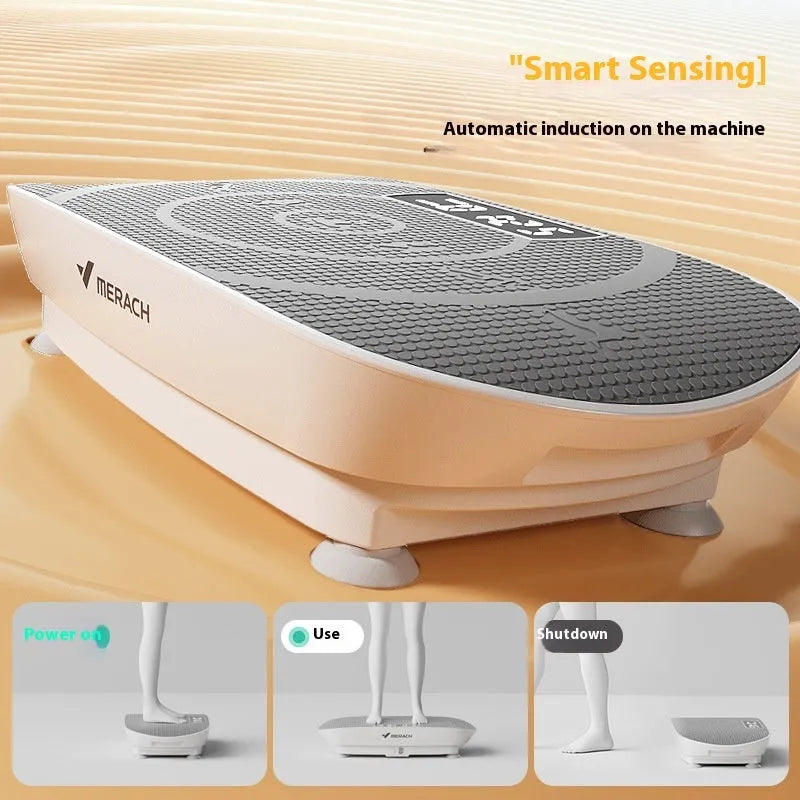 Grey portable vibration plate on a wooden floor, showing its slim 16cm profile and textured platform surface.