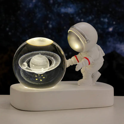 Glowing astronaut crystal ball night light with 6cm diameter and USB cable on wooden surface