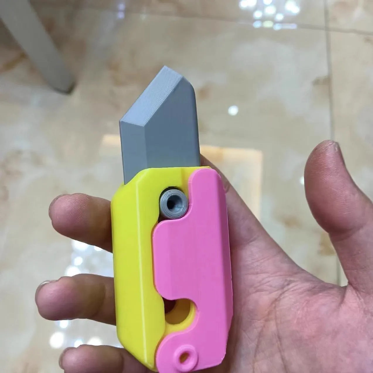 3D printed plastic carrot fidget knife with retractable blade, shown in orange and green colour scheme.