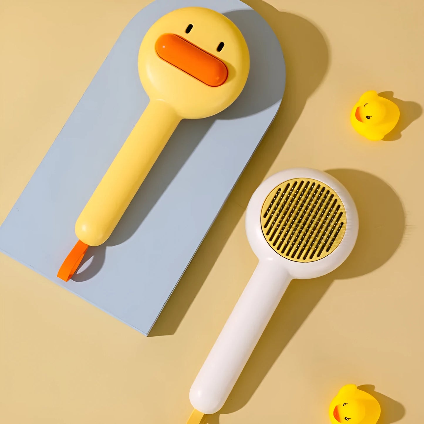 Small yellow duck-shaped plastic comb for grooming cats and dogs, with open needle teeth.