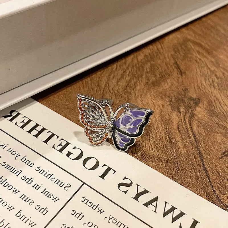Copper butterfly women's ring with an open loop design on a plain background.