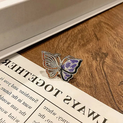 Copper butterfly women's ring with an open loop design on a plain background.