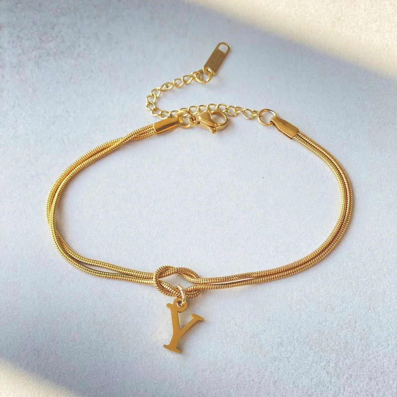 Elegant letter charm bracelets for women in gold and silver tones, featuring a delicate snake chain design and personalised letter charms.