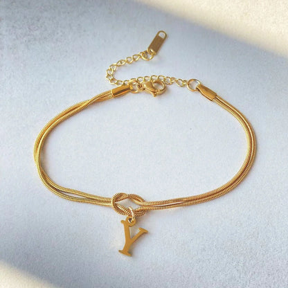Elegant letter charm bracelets for women in gold and silver tones, featuring a delicate snake chain design and personalised letter charms.