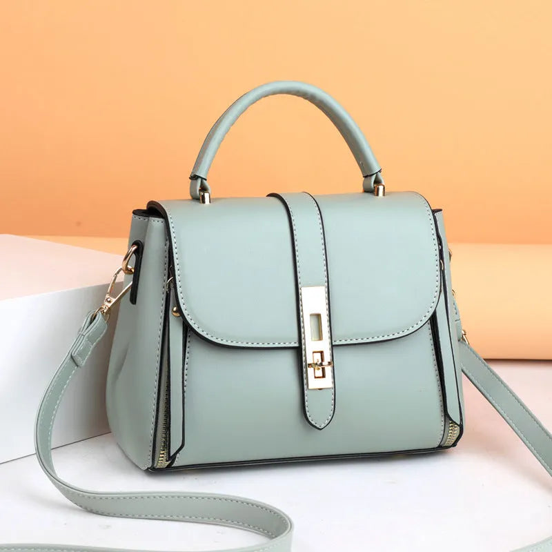 Women's soft black PU leather square messenger bag with a single shoulder strap on a table.