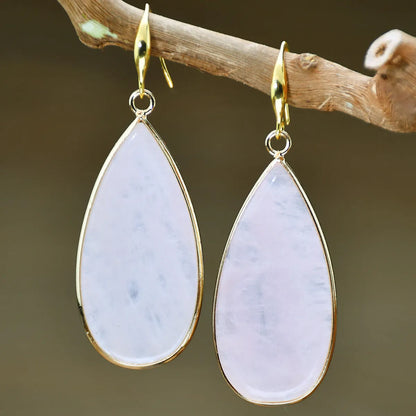 Handmade vintage long water drop earrings with tigereye stone and sterling silver hooks on a textured background.