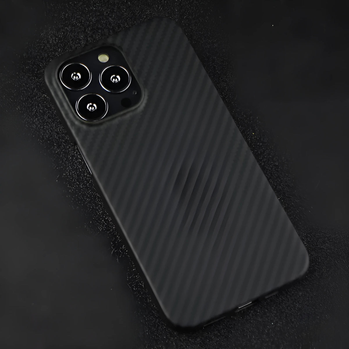Matt black Kevlar fibre iPhone case with volcano crater texture shown on an iPhone 14 Pro.