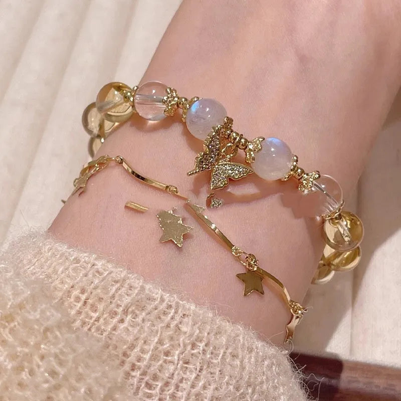 Close-up of a citrine-coloured crystal bracelet with diamond-shaped beads and a butterfly charm.