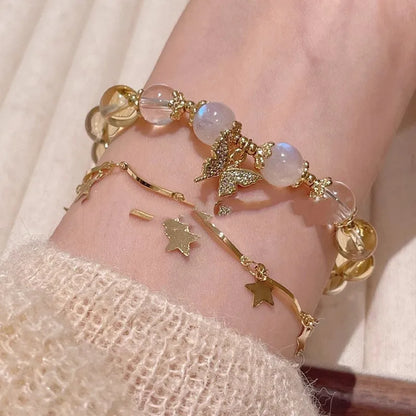 Close-up of a citrine-coloured crystal bracelet with diamond-shaped beads and a butterfly charm.