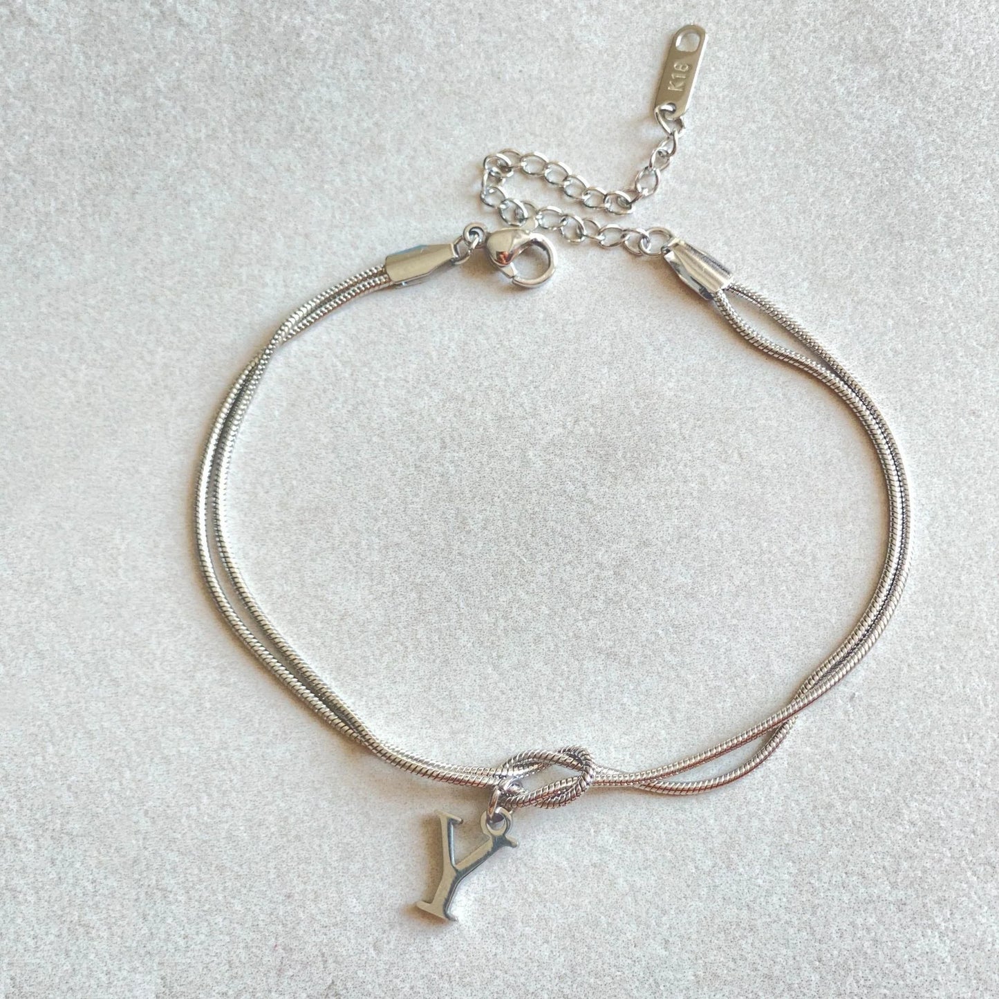 Elegant letter charm bracelets for women in gold and silver tones, featuring a delicate snake chain design and personalised letter charms.