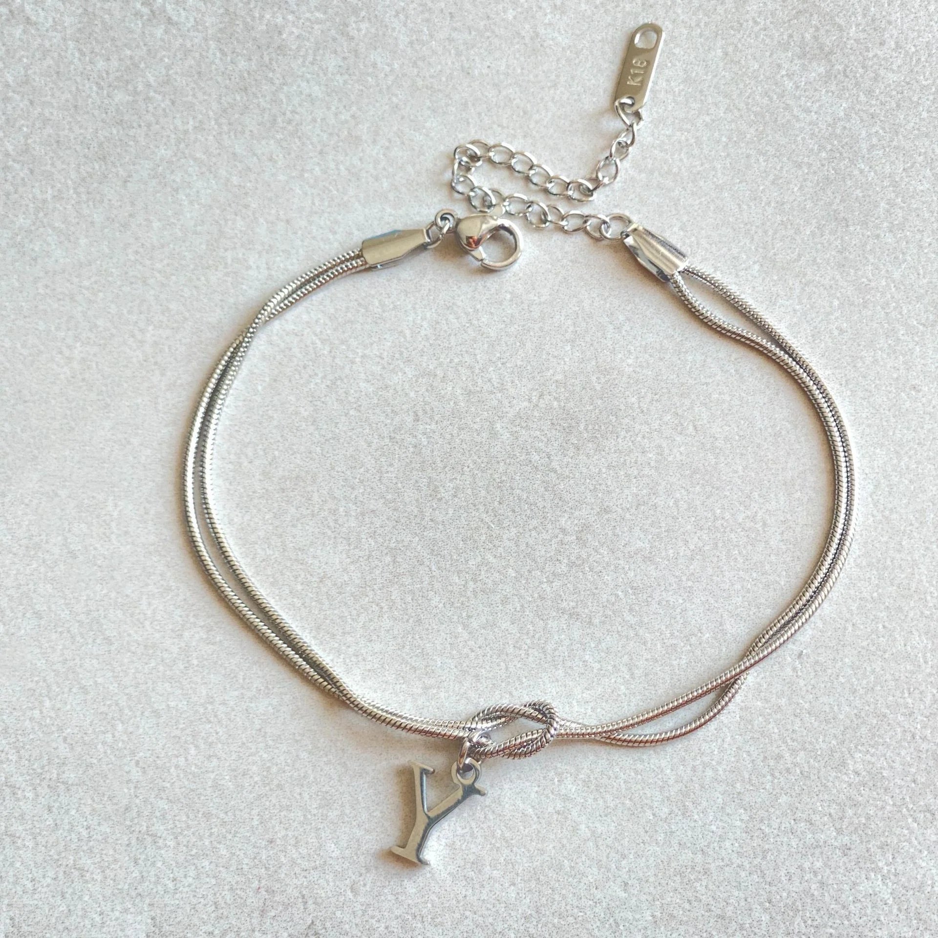 Elegant letter charm bracelets for women in gold and silver tones, featuring a delicate snake chain design and personalised letter charms.