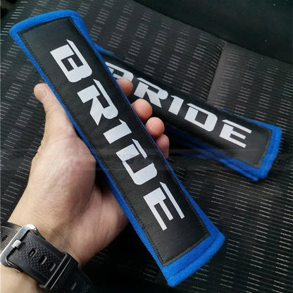 Car seat belt shoulder pad protectors in black, blue, and red colours with embroidered woven detailing